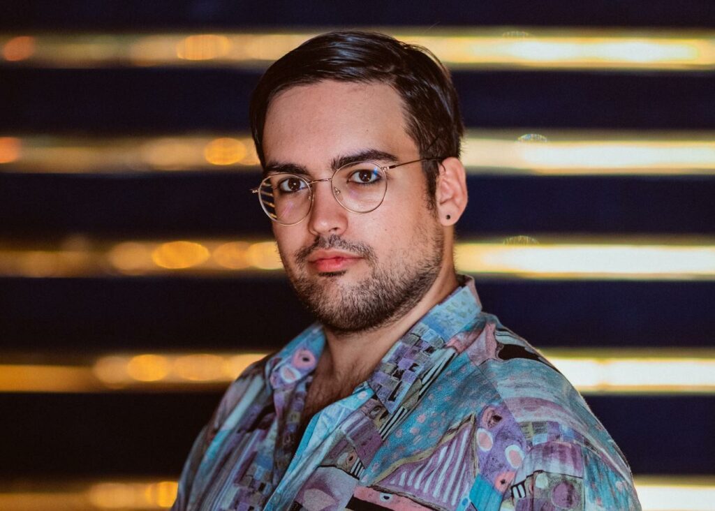 Portrait de Tristan Kopp, avec lunettes et chemise à motifs.
